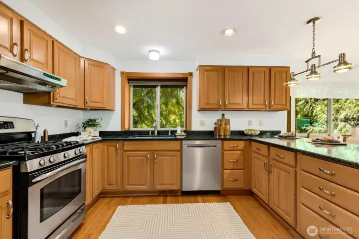 Large kitchen complete with over the sink window, cooktop vent and custom lighting over the additional counterspace eating area