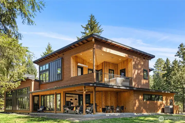 The lower-level wraparound patio creates an ideal outdoor hub with cooking, seating, and a firepit area, while the upper deck features a private hot tub retreat.