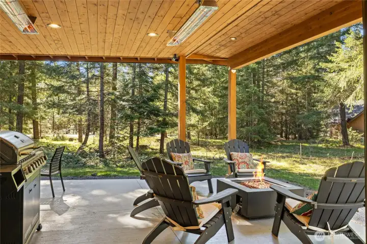 The spacious covered patio accommodates both a cooking and dining area, along with a dedicated firepit space, while overhead heaters ensure year-round comfort.