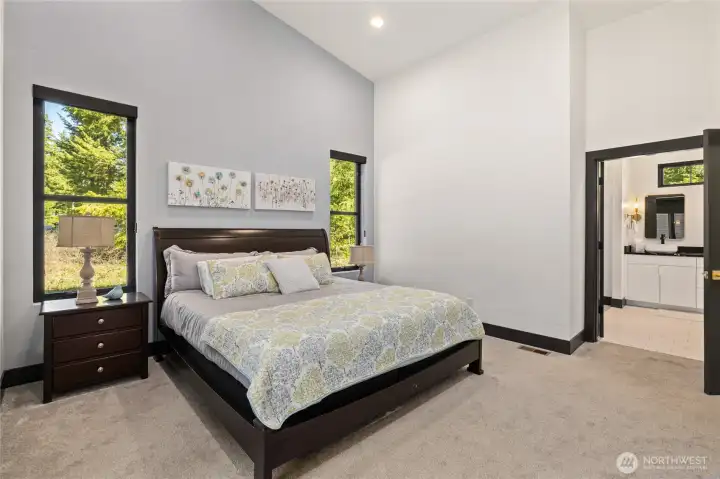 The primary suite features vaulted ceilings and tall windows, offering both generous space and ADA-compliant design.