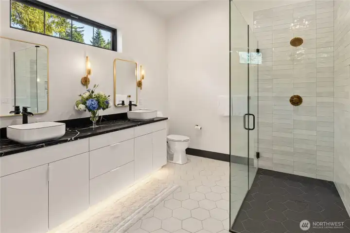 The primary suite includes a double vanity with spa style vessel sinks, a stunning tile shower, and radiant-heated tile floors, combining luxury finishes with ADA-compliant design.