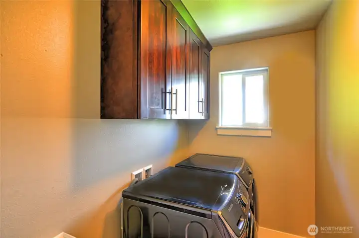 Upstairs laundry room with built-in cabinetry and storage.