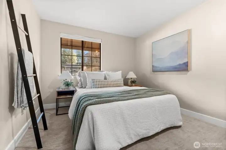 Cozy carpeted bedroom featuring a large window with blinds, filling the space with natural light while offering privacy and comfort.