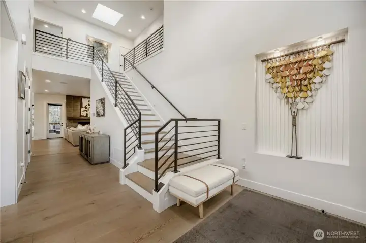 A bright two-story entry welcomes you with wide-plank floors and clean architectural lines. The open staircase creates a striking focal point, enhancing the home’s sense of space and modern elegance. Thoughtful sightlines lead seamlessly into the main living areas for an inviting first impression.