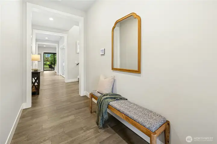 A welcoming entry hallway showcases rich hardwood flooring, crisp millwork, and a calming neutral palette that sets the tone for the home’s refined design. Clean sightlines lead toward the open-concept living spaces and backyard beyond, creating an immediate sense of light, flow, and connection.