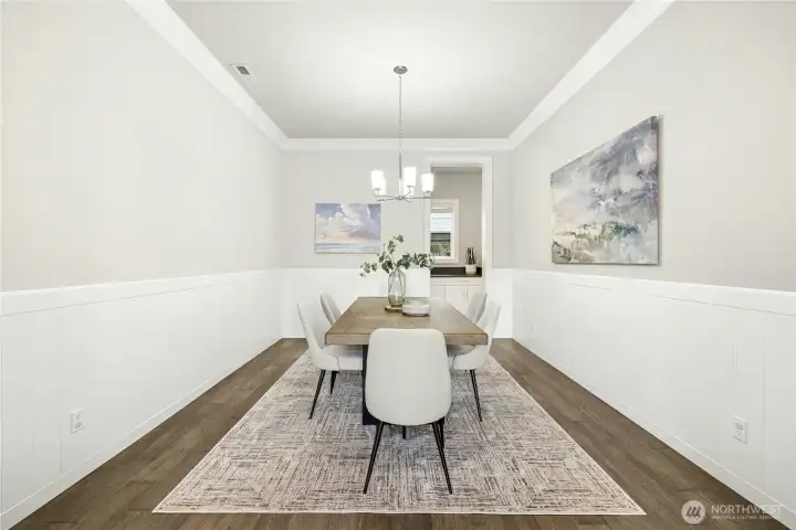 This elegant dining room features tray ceilings, crisp wainscoting, and contemporary lighting that elevate the space with subtle architectural detail. Neutral tones and warm hardwood flooring create a sophisticated yet welcoming setting ideal for both intimate dinners and larger gatherings.