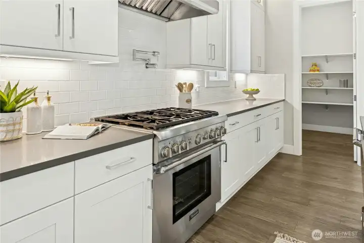 Premium Thermador range, full-height subway tile backsplash, and expansive quartz counters highlight the kitchen’s exceptional craftsmanship and attention to detail. A spacious walk-in pantry with open shelving provides abundant storage and everyday convenience just steps from the main cooking area.