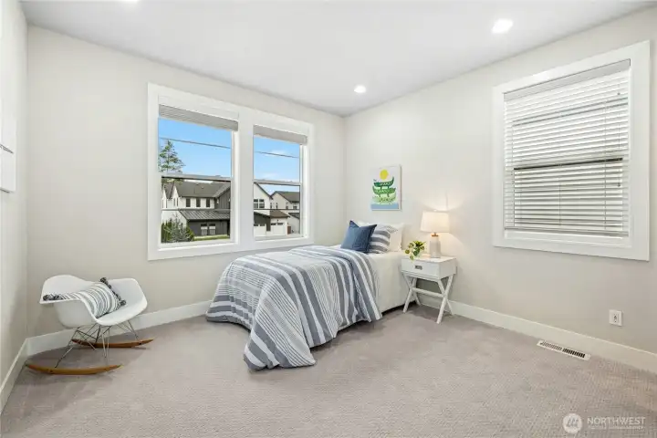 This bright secondary bedroom offers soft natural light from multiple windows. Neutral finishes and plush carpeting create a welcoming space that easily adapts to a variety of needs.