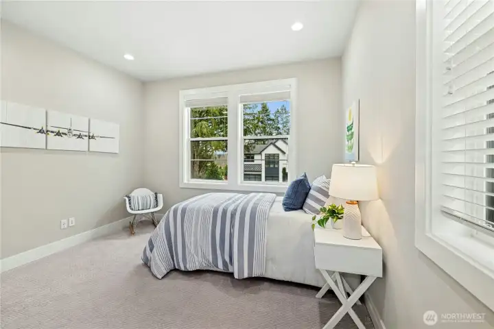 An alternate view of the first secondary bedroom highlights its bright corner placement and comfortable proportions. Generous windows provide abundant natural light while neutral finishes create a versatile space ready to personalize.