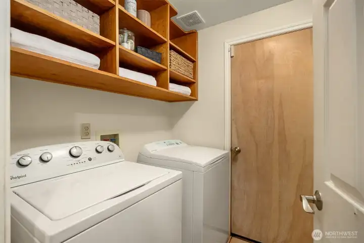 The laundry room has a full sized washer and dryer with storage.