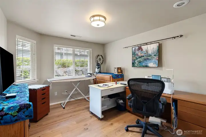 Second bedroom featuring durable, easy-maintenance flooring consistent with the primary suite. This versatile space is currently utilized as a sewing room but offers endless possibilities as a dedicated home office, hobby room, or comfortable guest bedroom.