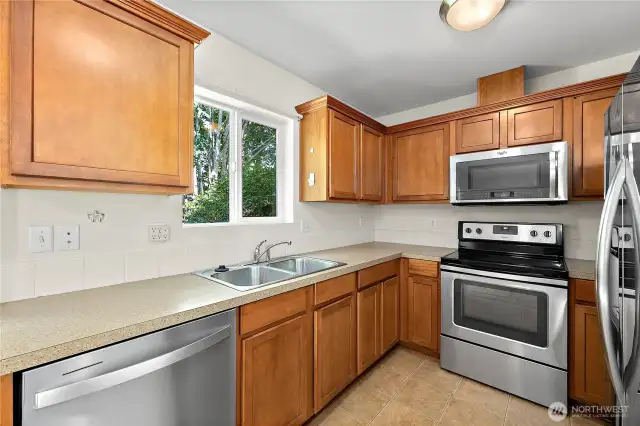 Kitchen right off living room featuring maple cabinets offering ample amount of storage space.