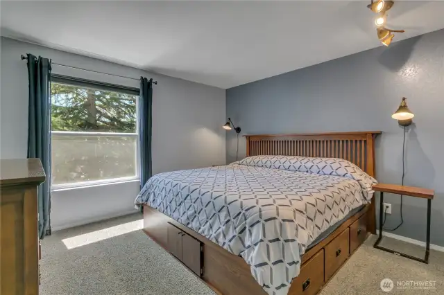 The primary bedroom has a view of the treed area plus custom, built-in shelving in the closet.