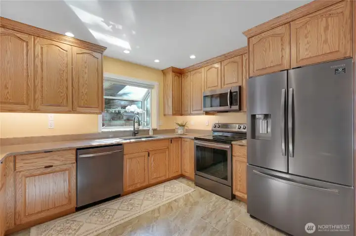 Spacious kitchen with extensive oak cabinetry, large peninsula with seating, stainless appliances, and great prep space—ideal hub for everyday living and entertaining.
