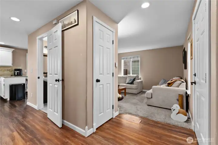 Entry view of living room to the right and half bath + hallway to kitchen to the left