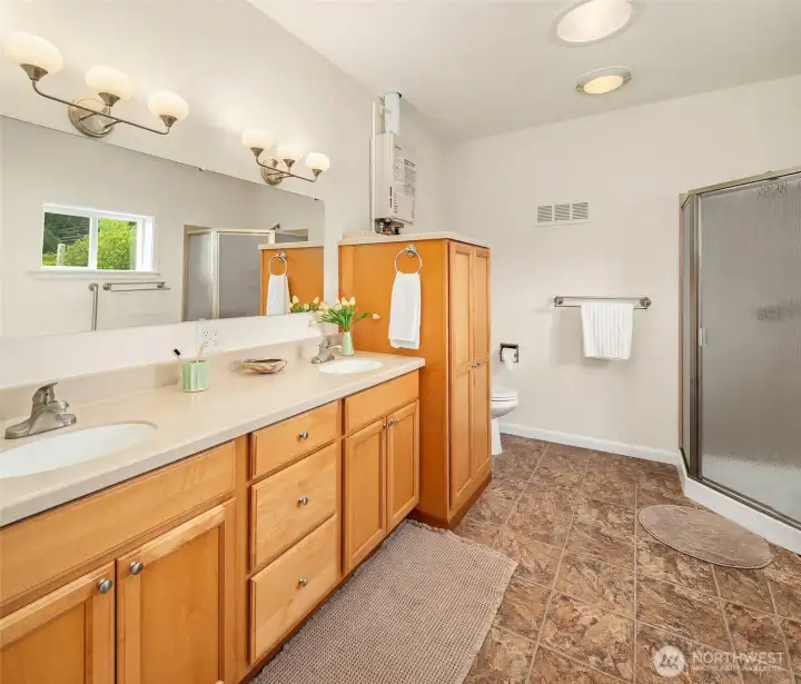 3/4 bath with lots of cabinetry and two sinks. Water heater is natural gas, on-demand. Washer and dryer share this space.