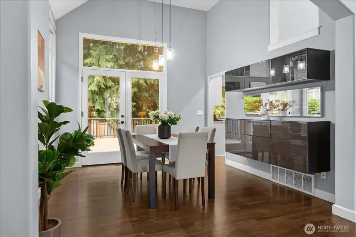 Light-filled modern dining space featuring sleek floating cabinetry, rich wood tones, and dramatic pendant lighting