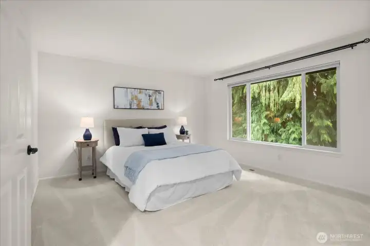 Serene primary suite with stunning forest views, high ceilings and fresh carpeting.