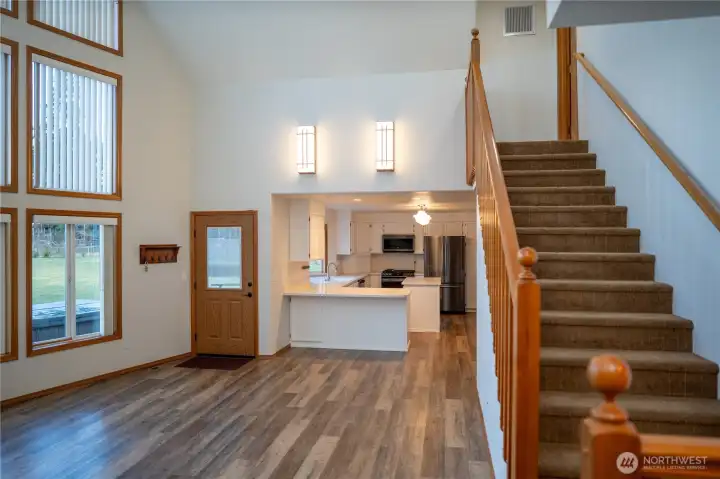 View of family room, looking toward kitchen. Stairway leads to second primary suite upstairs