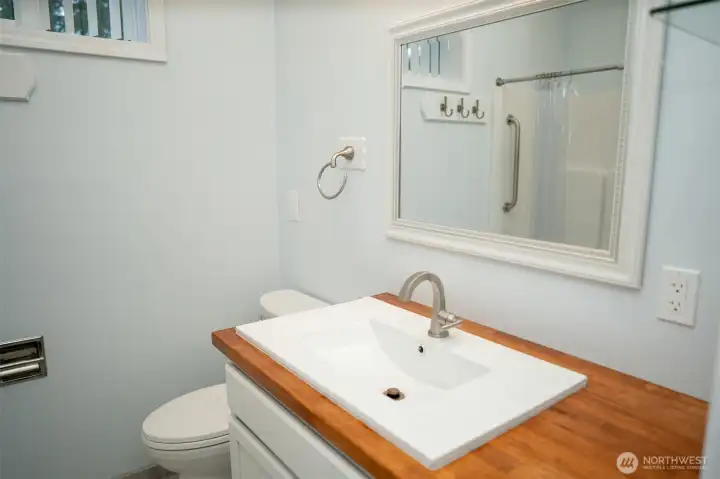 Main floor primary bath with handsome wood counters, crisp white finishes