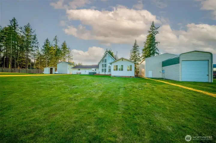 From the back, home with shop and storage shed to the left, hangar with drive through bump out to the right