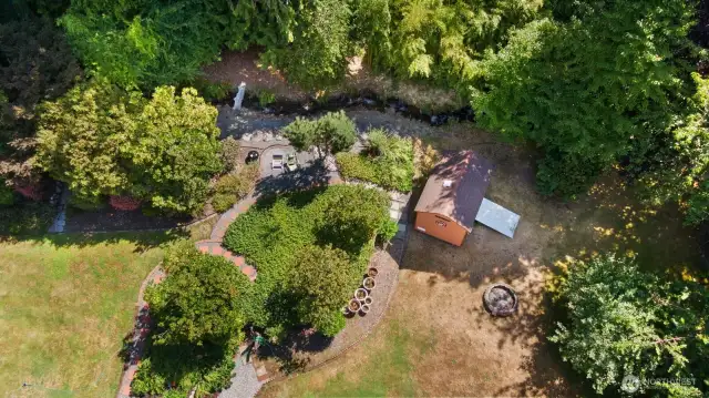 Mature landscaped lower acreage with Mud Creek running along the E property line and garden storage shed