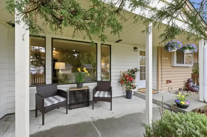 Welcome home to your cozy, covered front porch, surrounded by lush greenery and fenced front yard