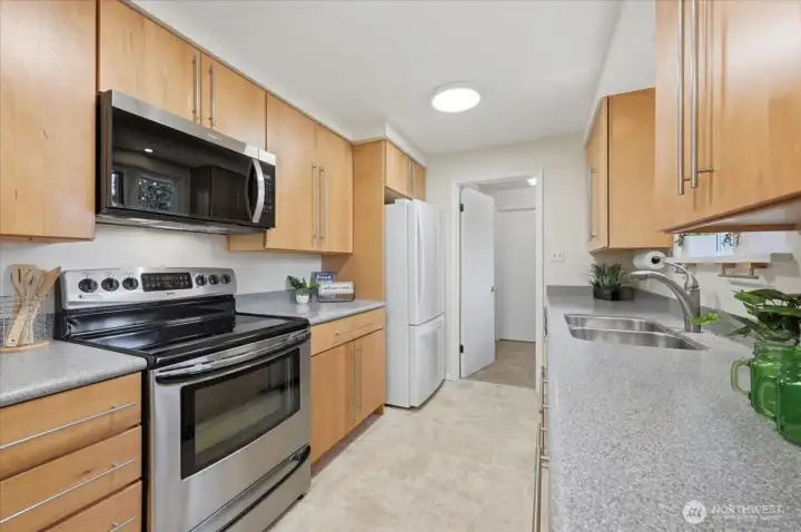 Upgraded maple cabinets & hardware, pantry not pictured, Stainless Steel range, microwave & dishwasher plus great refrigerator, newer counters, and new light fixtures make this kitchen ready for your chef skills!  Plenty of counterspace and access to 3/4 bath with laundry, door to your backyard oasis and or leads upstairs to your 1/2 story, quaint 3rd bedroom.  Also leads to the secondary living room space creating a functional, circular floor plan!