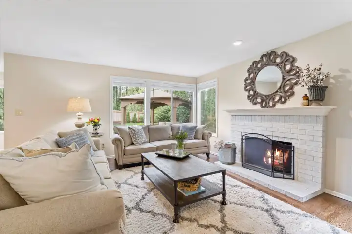 The kitchen opens to an open-concept living room, centered around a warm, wood-burning fireplace that creates an inviting and connected gathering space.