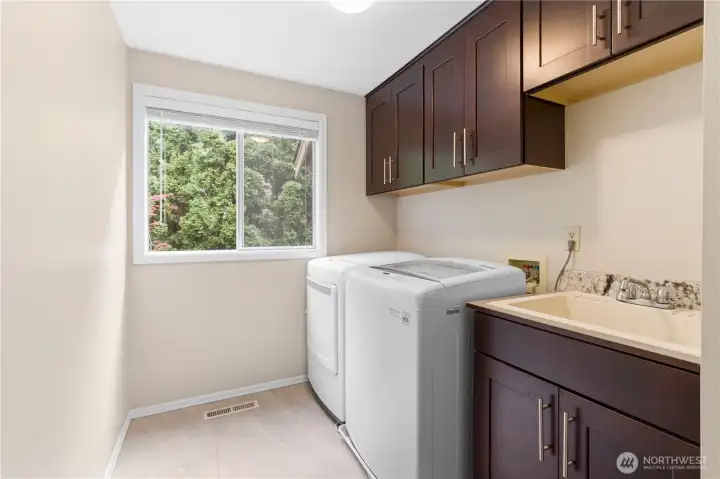 The main floor features a convenient utility room complete with a utility sink, LG washer and dryer, and durable luxury vinyl plank flooring.