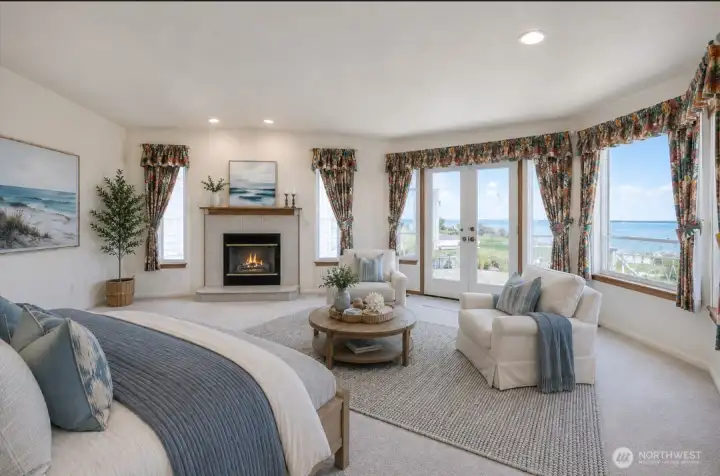 Virtually staged primary bedroom with sitting area and gas fireplace.  French doors open up to the water!