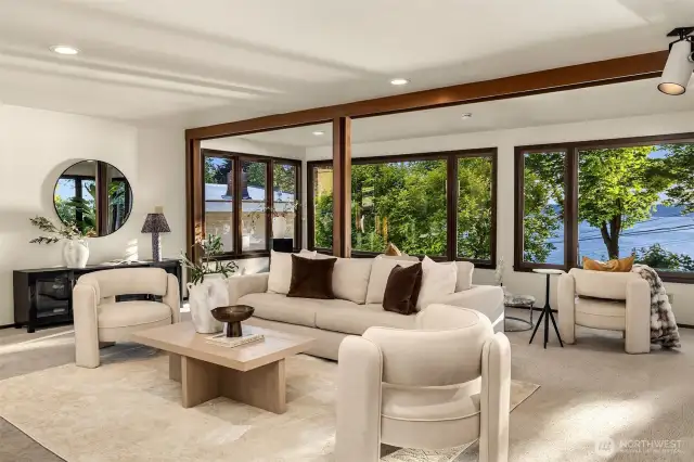 Inviting and comfortable, the living room opens onto west facing exposure, water and a natural view. Note that the current owners favored a more treed feel however one controls the water views as the property comes with the beach parcel.