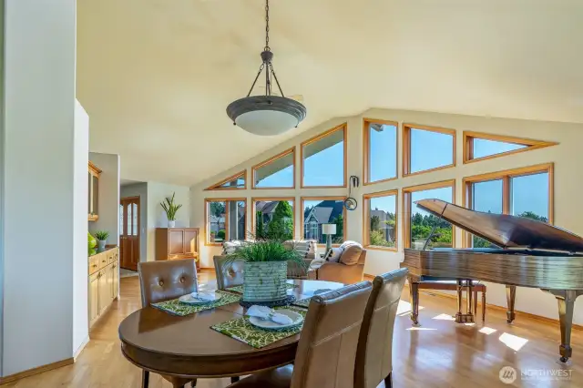 From the dining area, take in the soaring ceilings, custom windows, and sun-drenched great room—framing lush neighborhood views and distant mountain silhouettes. This open layout invites beauty and light into every daily moment.