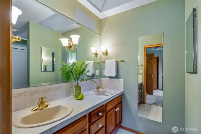 The primary bath offers a timeless layout with dual sinks, ample counter space, and vaulted ceiling detail for added height and airiness. A practical and peaceful start to your day!