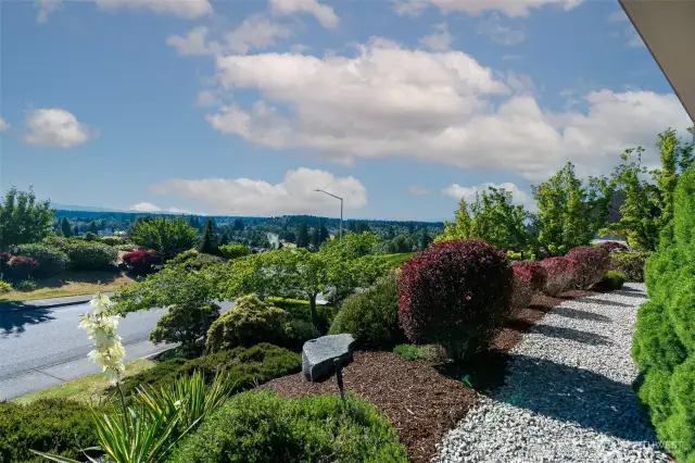 Manicured landscaping and vibrant seasonal color line the path, leading your eye to sweeping territorial views and the peaceful natural beauty beyond.