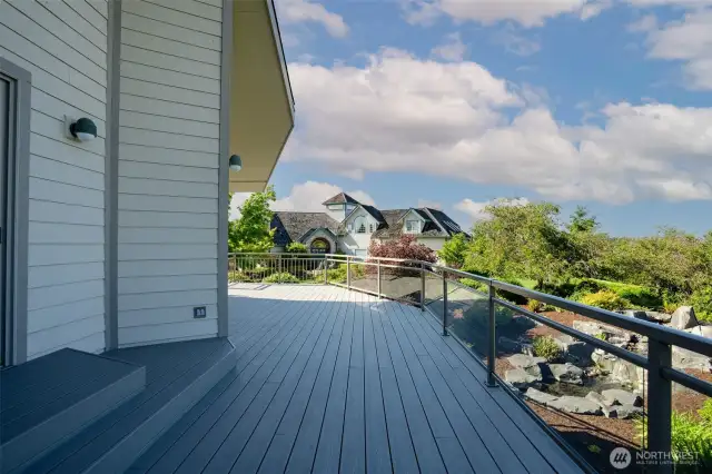 Step outside to this wide, elevated deck that seamlessly blends comfort and scenery—ideal for gatherings or relaxing with views of the lush, manicured landscape below.