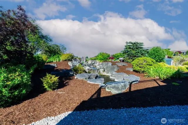 A tiered water feature winds through the landscaped yard, creating a serene garden focal point below the view deck—perfect for outdoor relaxation or entertaining in style