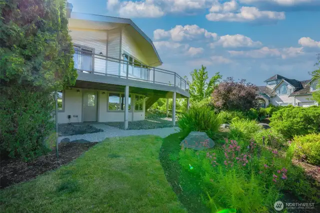 Step into your own backyard retreat—lush gardens, open lawn, and tiered landscaping surround this generous outdoor space, all viewed from the oversized upper deck.