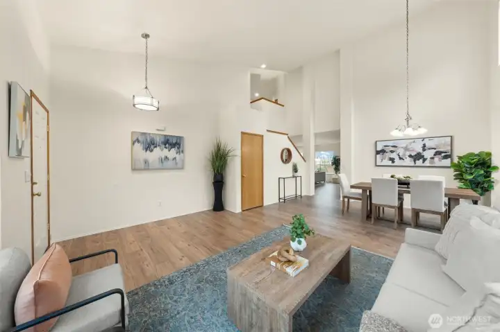 An expansive great room features vaulted ceilings, modern lighting, and a flexible layout ideal for both relaxing and hosting. The open sightlines to the dining area and stairway add dimension and a sense of space throughout the main level.