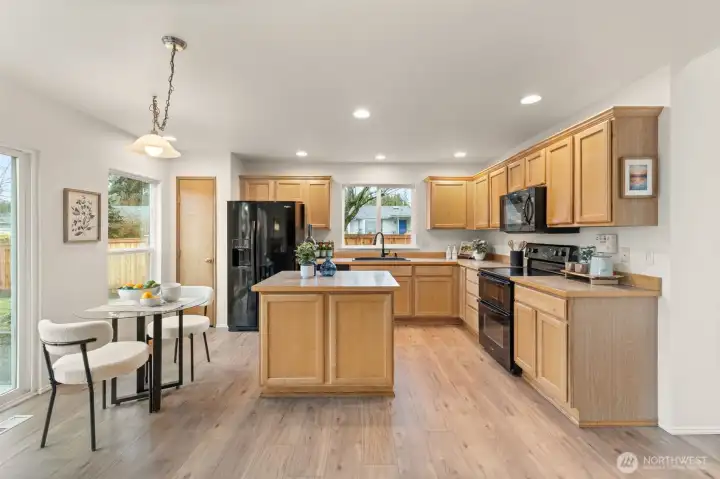 A large center island provides generous prep space and doubles as a hub for casual meals or conversation. Recessed lighting and extensive cabinetry support both function and organization.