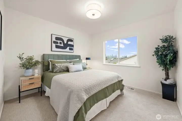 Bedroom 2 features soft carpet and a large window that brings in great daylight and outdoor views. Notice the updated light fixture here and throughout the bedrooms.