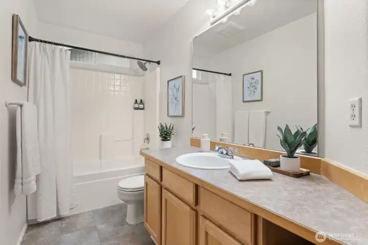 The main bath offers a clean, functional layout with a single-sink vanity, generous counter space, and classic finishes that keep the space timeless. A tub/shower combination and durable flooring make this bathroom well-suited for daily use and guests alike.