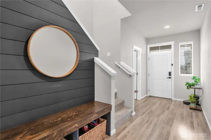 As you enter, you will find gorgeous flooring and this built-in bench with gorgeous slat wall. Steps up and powder room door ahead to left.