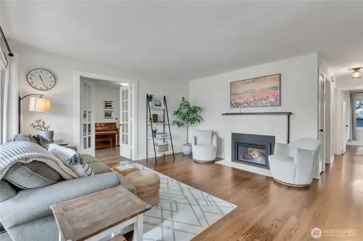 Spacious living rom with gleaming refinished hardwood flooring & lovely natural gas fireplace for cozy PNW evenings!