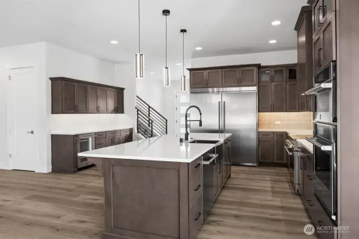 Warm, rich kitchen finishes. gleaming quartz countertops, 66" Frigidaire refrigerator/freezer, induction range, wall mounted microwave/second oven.