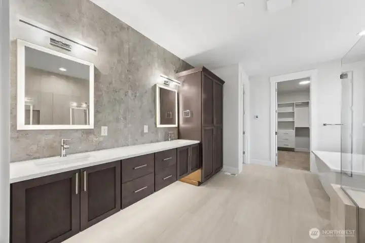 Spa-like primary bath with heated floors, extensive tile, backlit mirrors, and rich cabinetry.