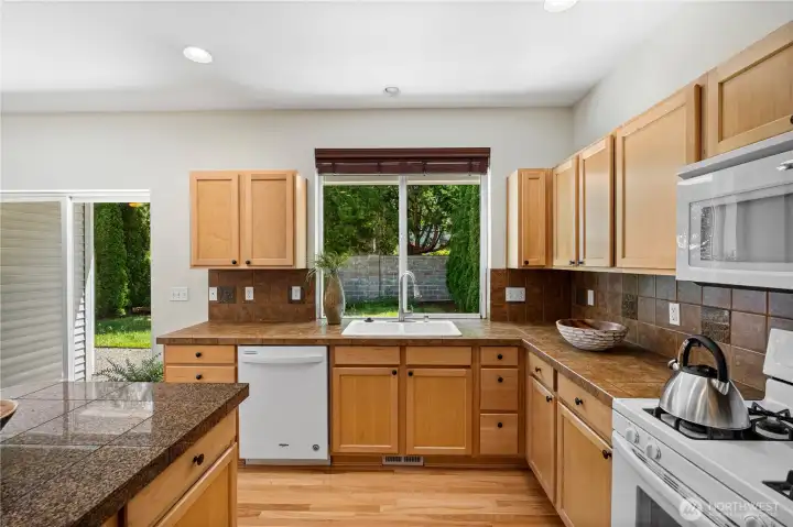 The well -appointed kitchen features beautiful refinished maple hardwood floors, tile countertops and  backsplash.