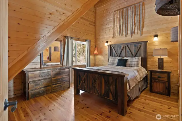 Upstairs, this bedroom has a fun "hayloft" feel with antique Texas barnwood doors over the window that looks over the loft/great room below!
