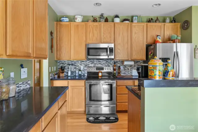 Kitchen has granite countertops, oak cabinets, real hardwood floors, tile backsplash, stainless steel appliances too!