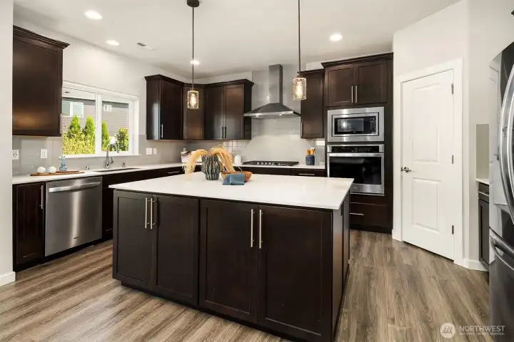 This kitchen has quartz countertops, newer appliances, new island lighting, lots of cabinets/storage and workspace! Behind the closed door is a walk-in-pantry.
